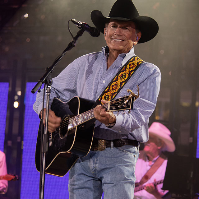 George Strait playing a guitar on stage.